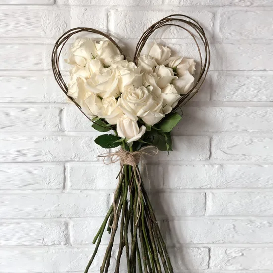 White roses formed into a heart shape against a brick wall