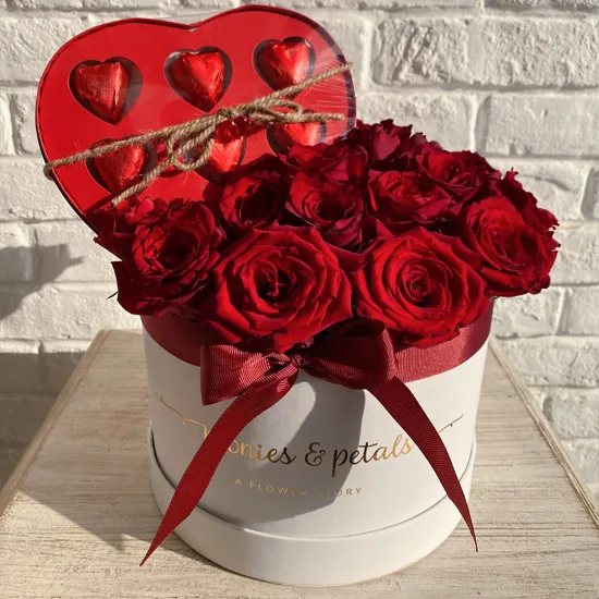 Red roses arranged in a box paired with a heart-shaped chocolate gift
