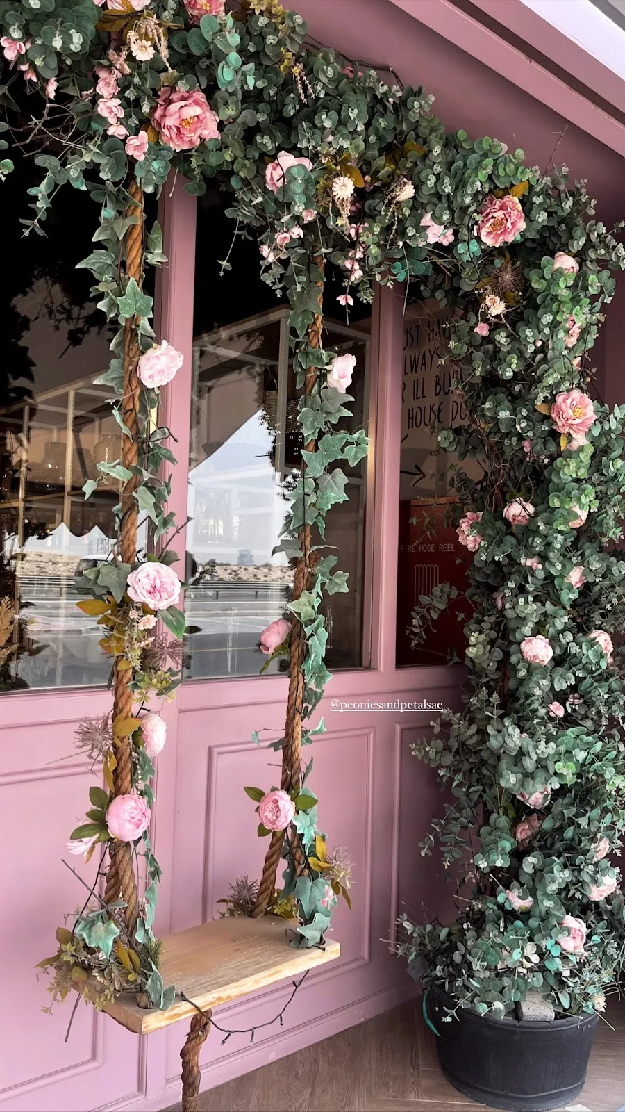Floral arch and rope swing framing the studio window, dressed in eucalyptus and pink blooms