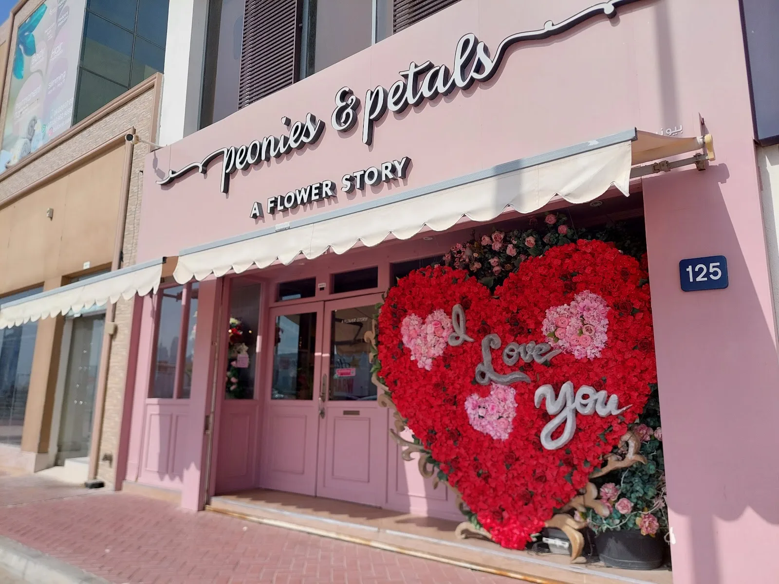 The storefront window dressed with a red floral heart reading I love you