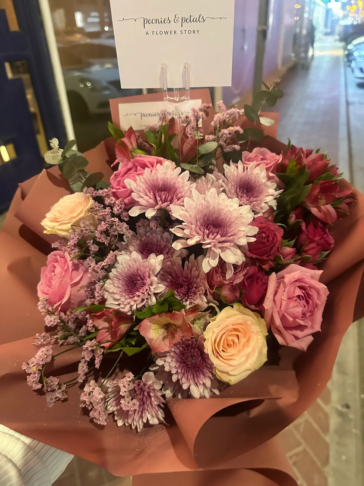 A mauve and pink bouquet held outside the studio at night