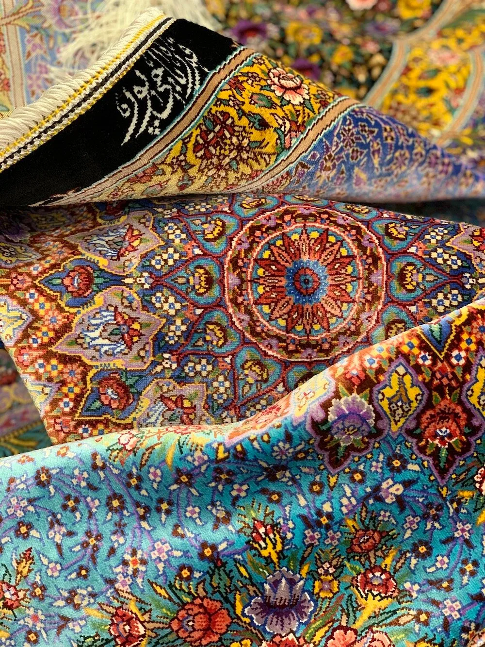 Stack of folded silk carpets showing many medallion designs