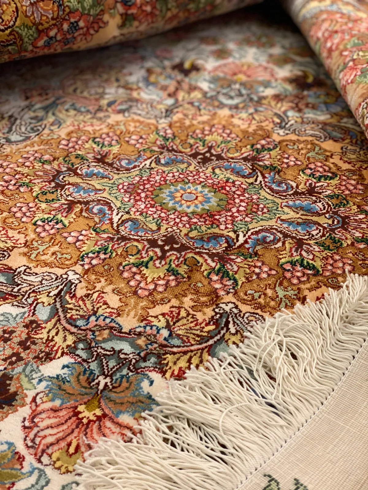 Coral-ground silk carpet with intricate floral medallion and fringe