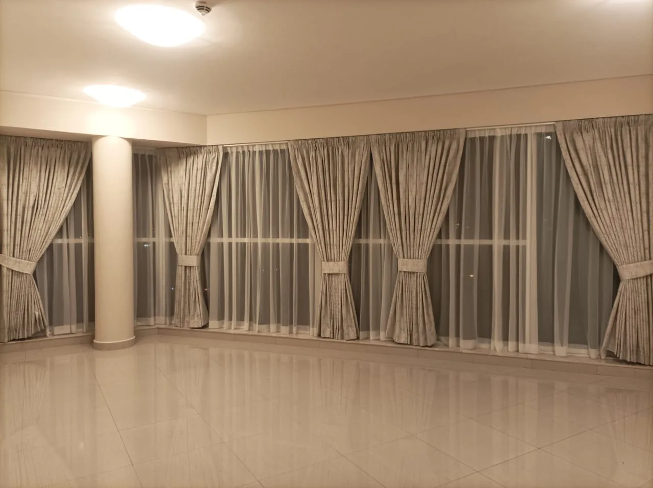 Pleated curtains with tie-backs across a wide hall