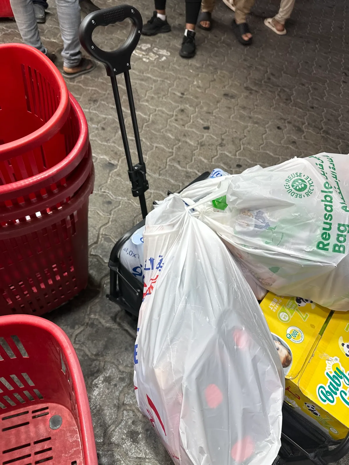 Stack of red shopping baskets and a loaded trolley at the Gifts Village entrance