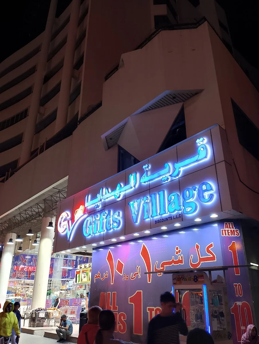 Gifts Village blue neon sign glowing at night above the entrance