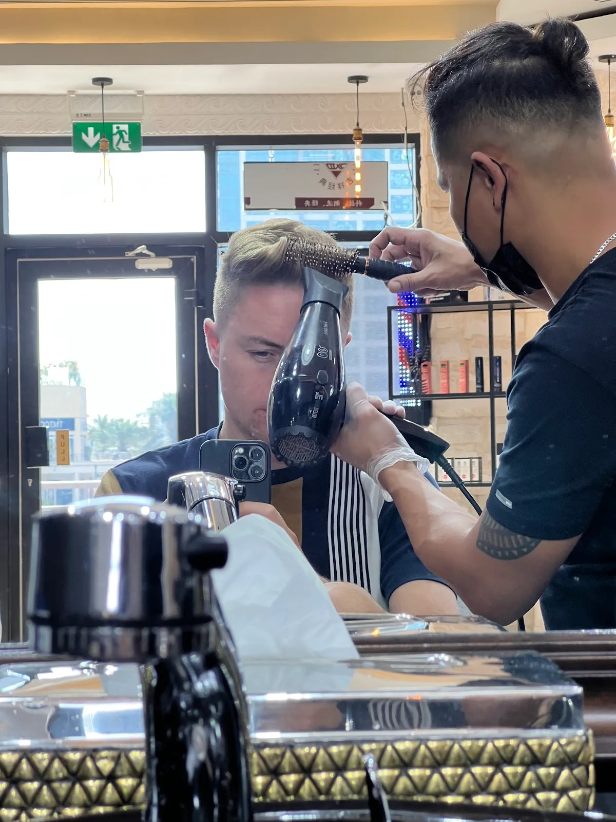 A barber blow-drying and styling a client's hair