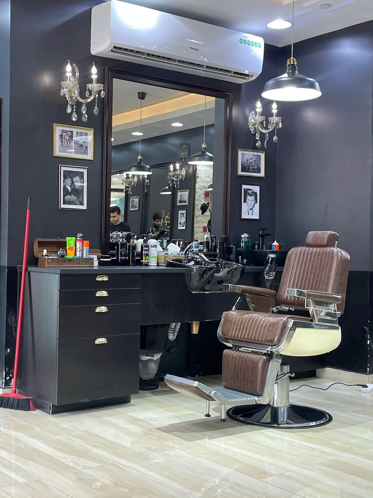 A single barber station with mirror, brass sconce and leather chair