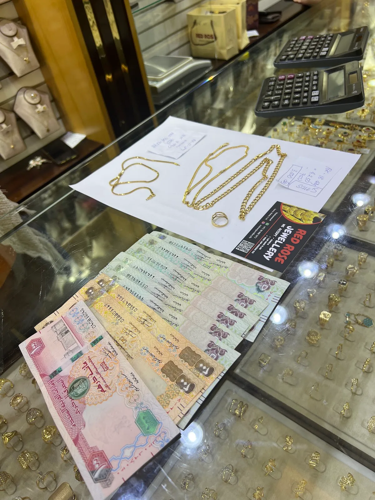 Gold chains, a ring and UAE dirham notes on the counter at Red Rose Jewellery during a gold sale