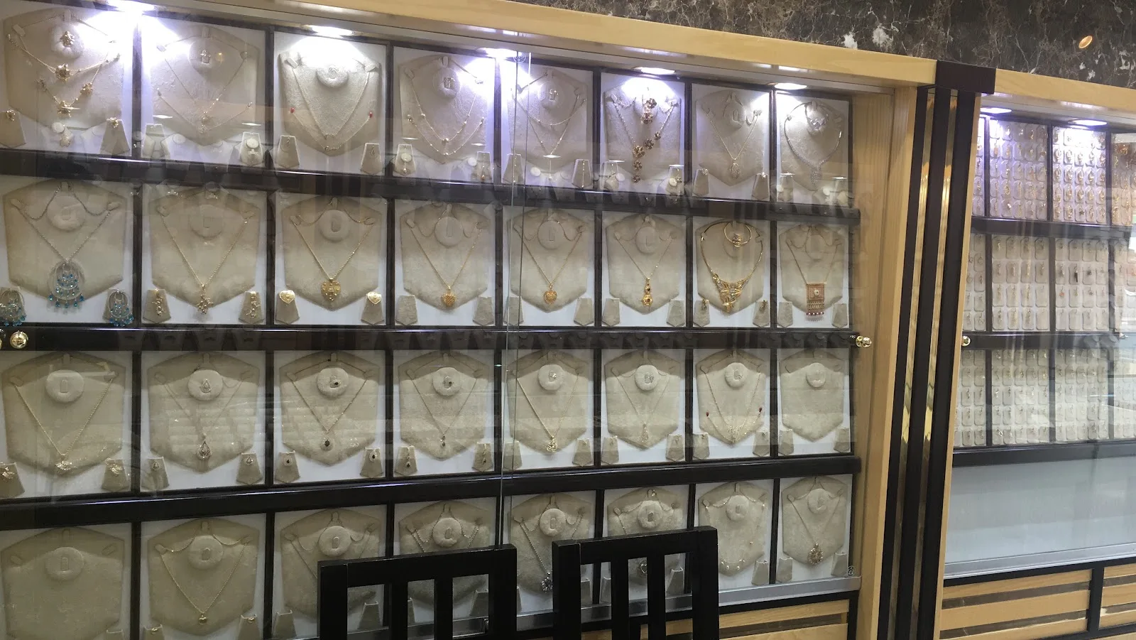 A glass case wall lined with gold necklaces and pendants at Red Rose Jewellery