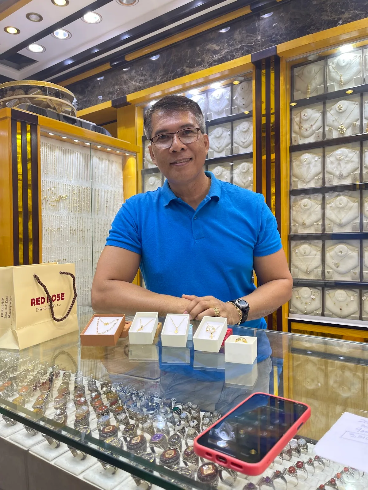 A member of the Red Rose Jewellery team presenting necklaces and a ring across the counter