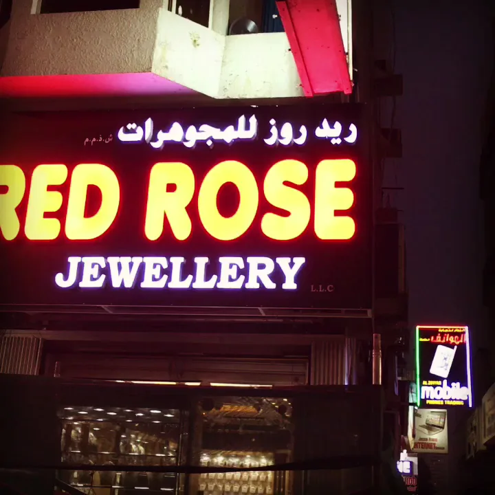 The illuminated Red Rose Jewellery shopfront sign on Al Satwa Road at night