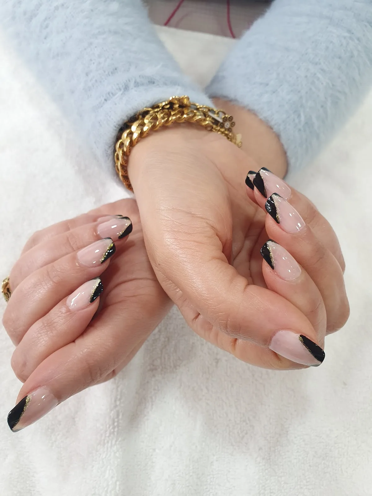 Almond nails with black and gold French tip design