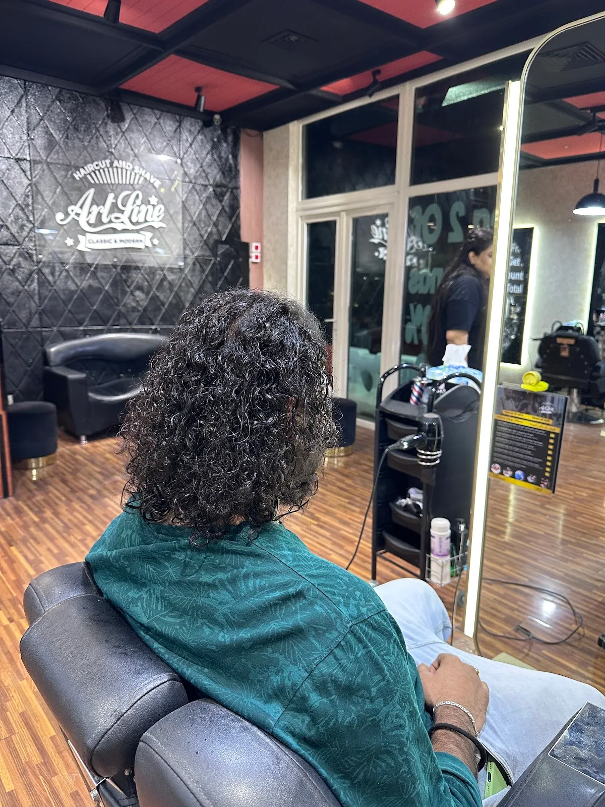 A client at an illuminated mirror station beside the ArtLine logo wall