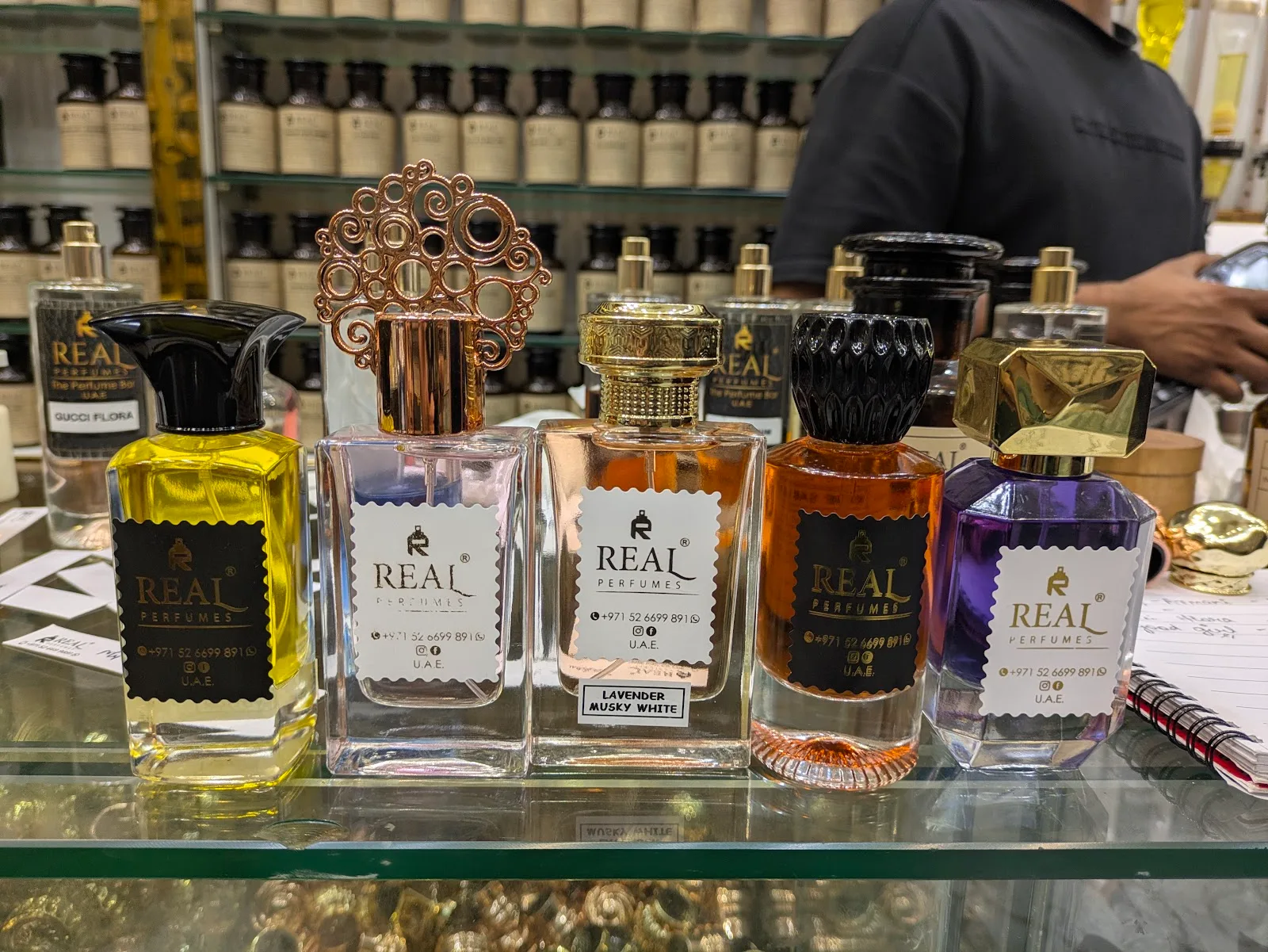 A row of bespoke Real Perfumes bottles filled with custom fragrance oils on the counter at the Deira perfume bar