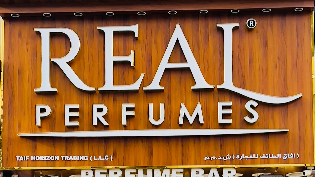 Close-up of the carved REAL PERFUMES wooden shop sign with silver and gold lettering