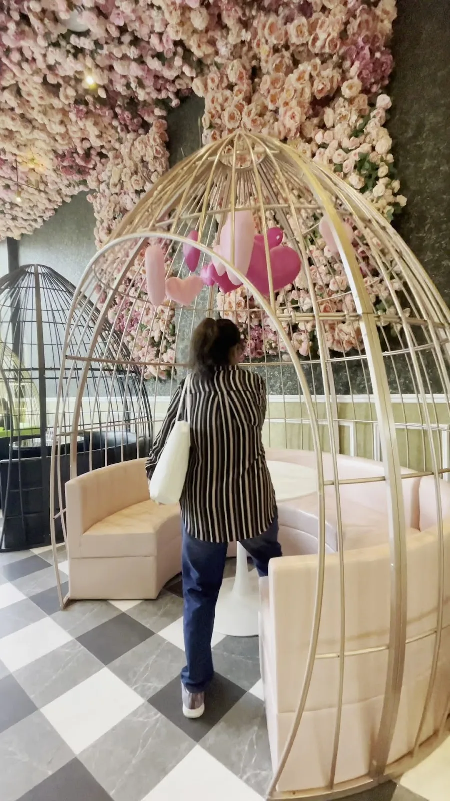 Guest beside the gold birdcage and rose wall