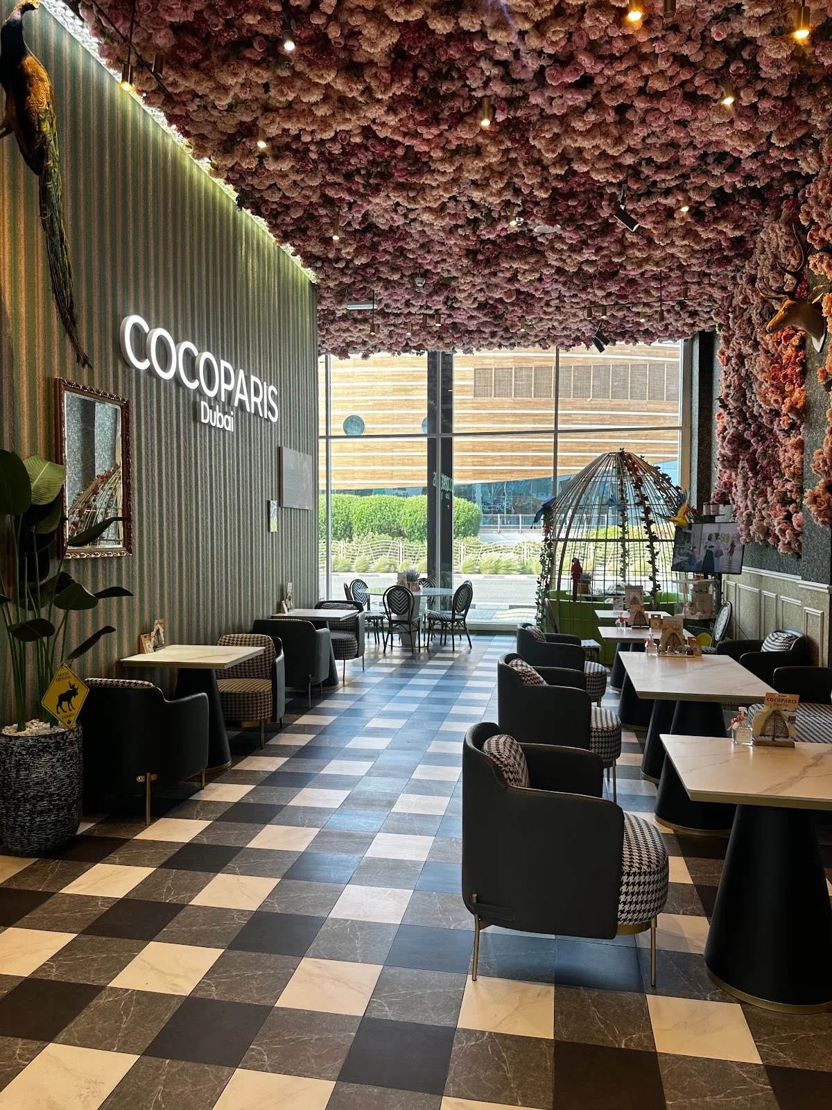 The flower-ceiling dining room at COCOPARIS Dubai with neon wordmark and checkerboard floor