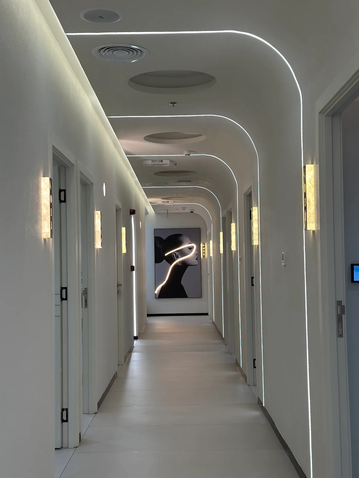 Curved neon-lit corridor of treatment rooms