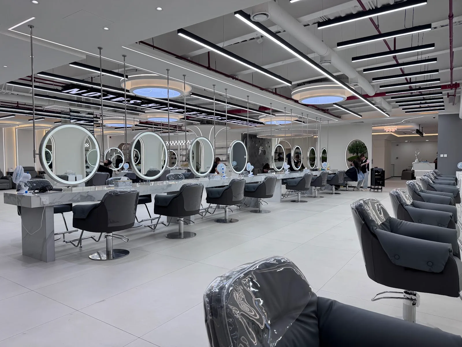Row of round LED mirror styling stations inside Diffany Super Hair Fixing Center, Dubai
