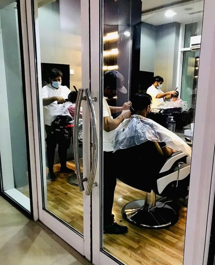 Barbers cutting hair seen through the glass entrance
