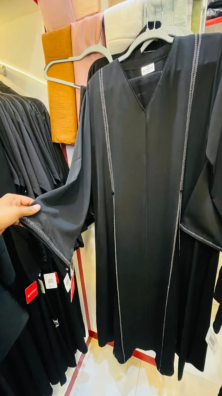 Black abaya on a hanger with fine chain-stitch detailing