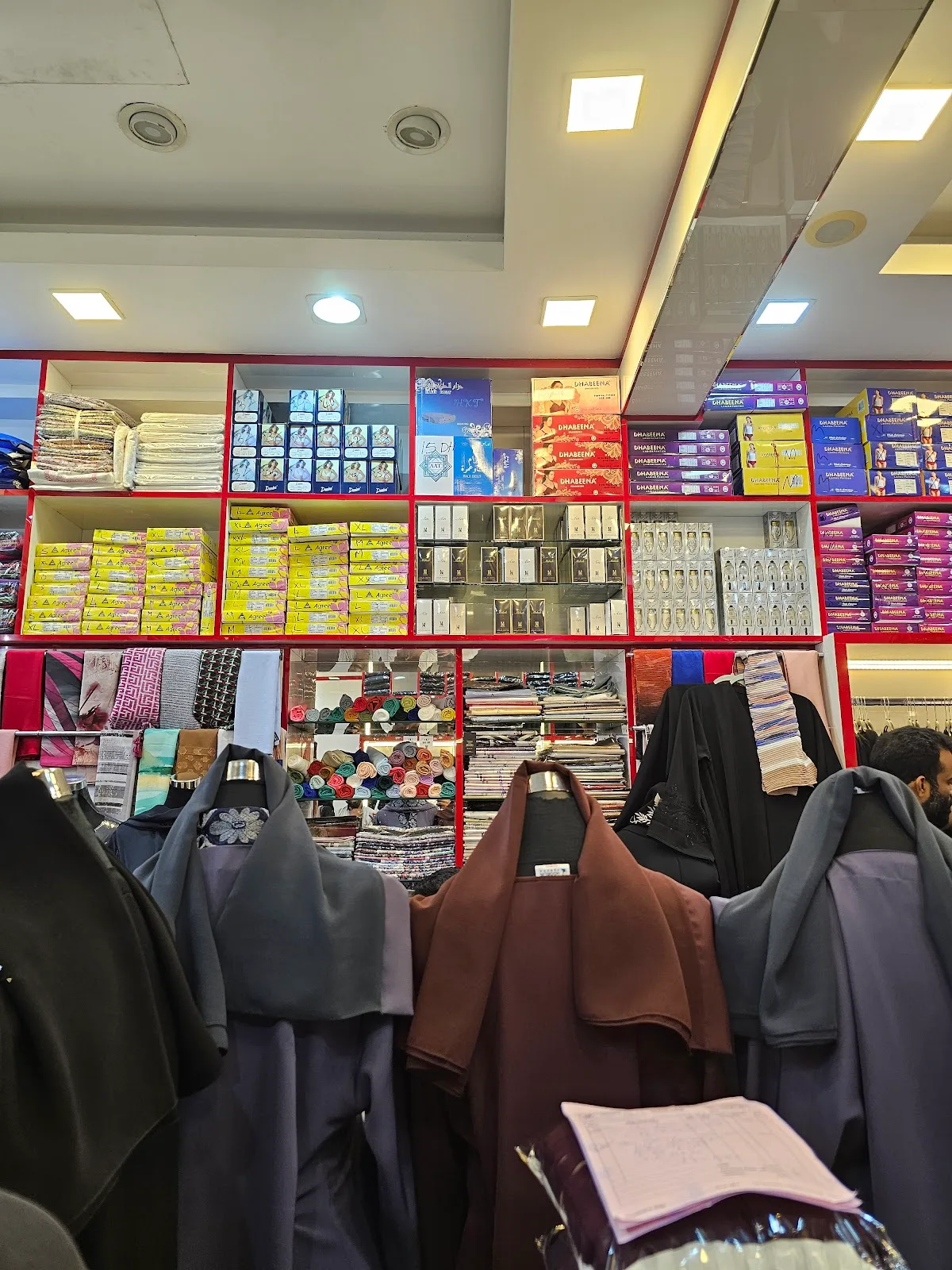 Interior shelves of boxed goods and abayas inside the store