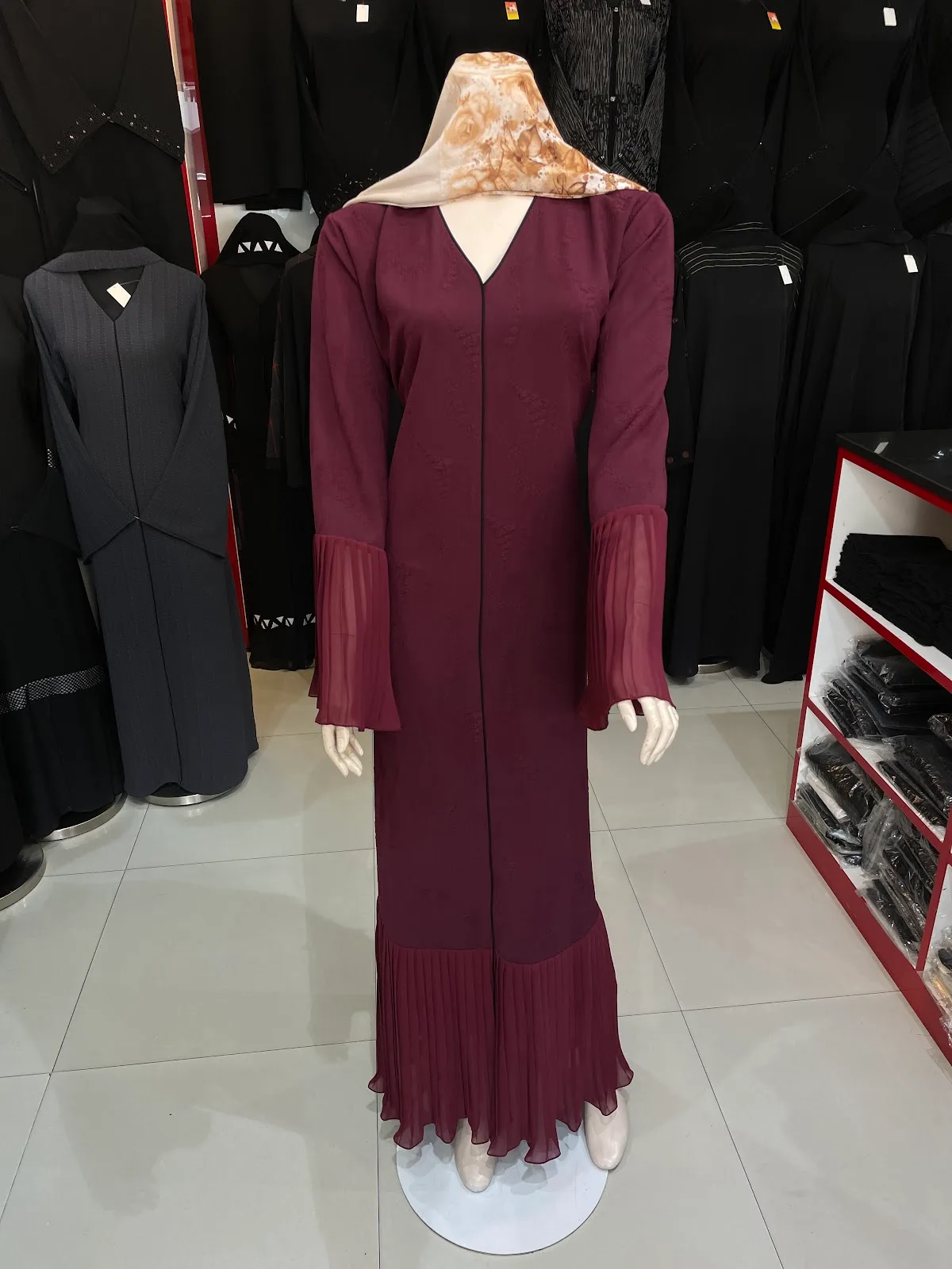 Burgundy abaya with pleated chiffon cuffs on display