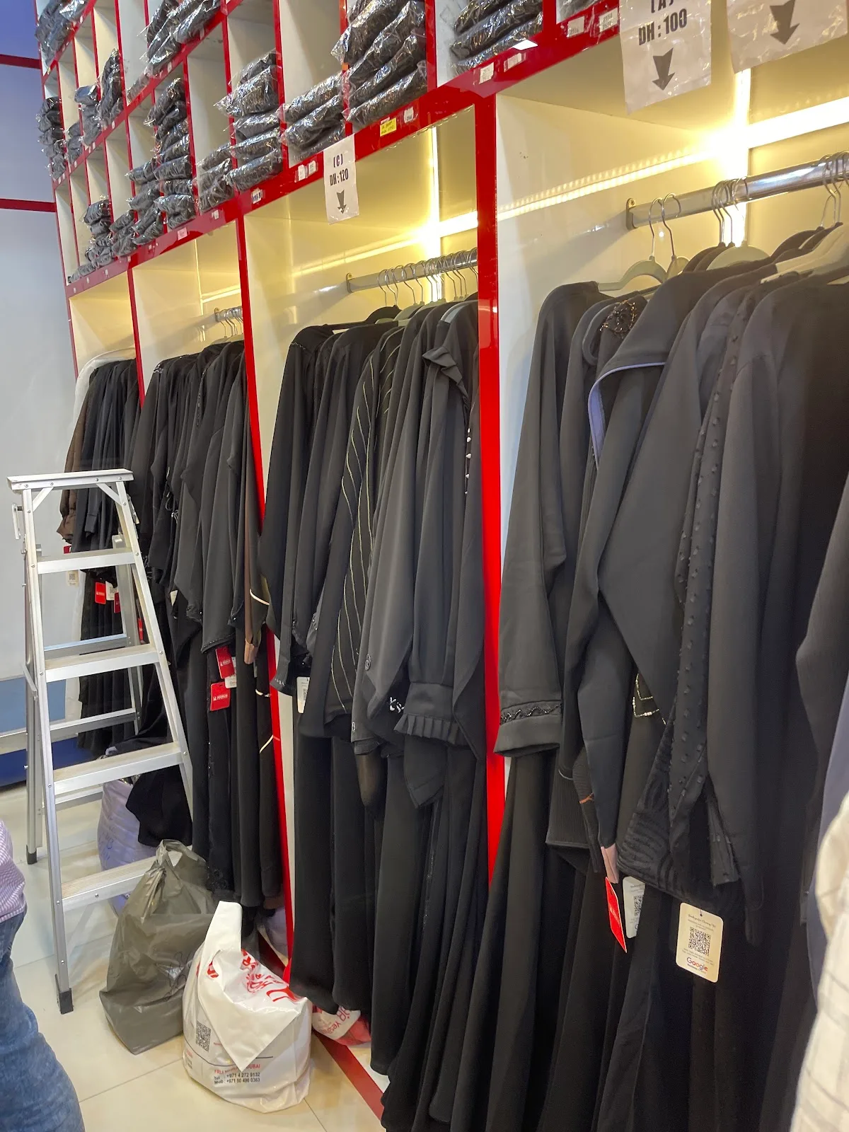 Racks of black abayas with red shelving inside Hoorlin Pardha