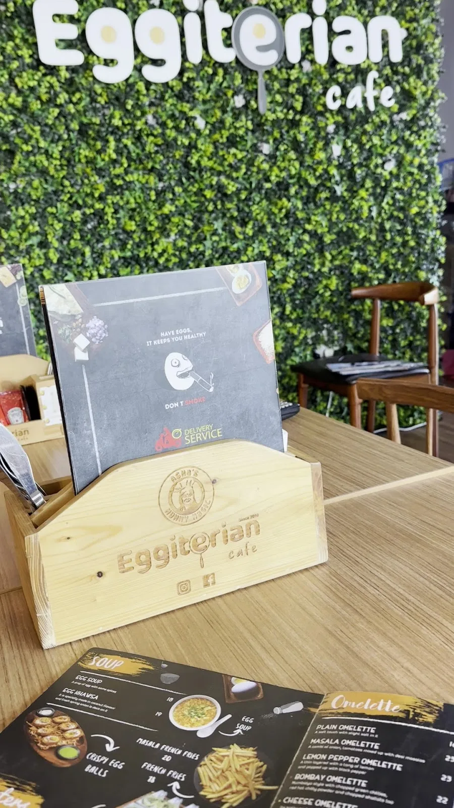 Eggiterian Cafe interior with its lush green living wall and glowing wordmark sign above the table caddy