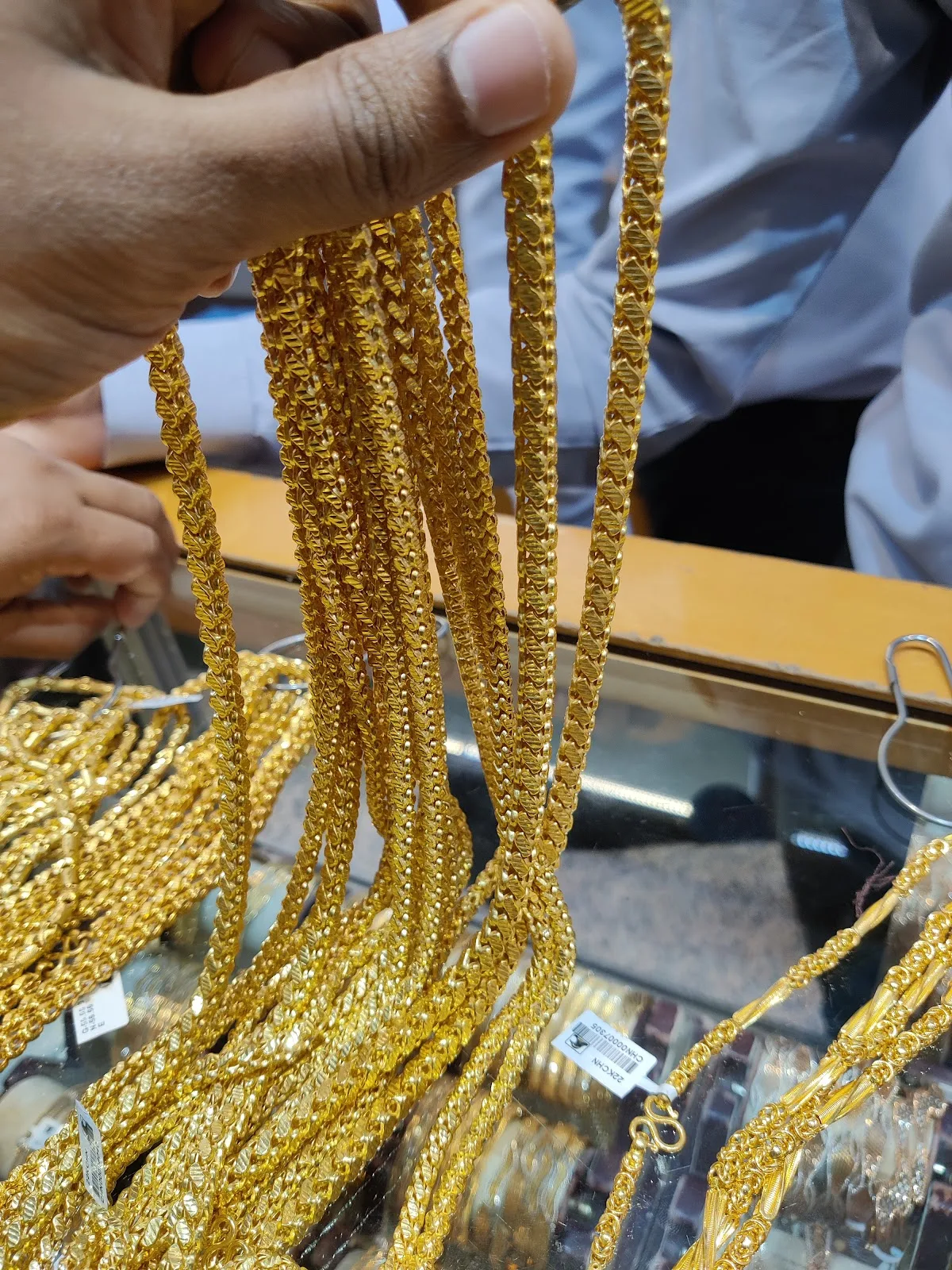 Strands of gold chains held over a display counter
