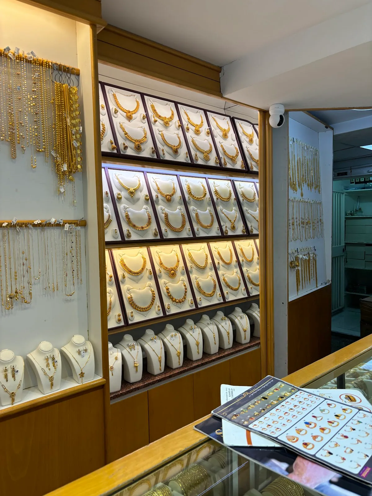 Backlit wall display of 22K gold necklace sets at Chittilappilly Jewellers