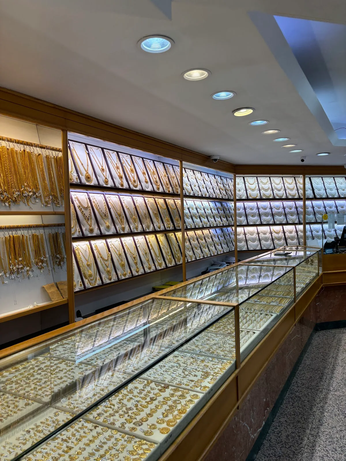 Long glass display counter and gold necklace wall inside the showroom