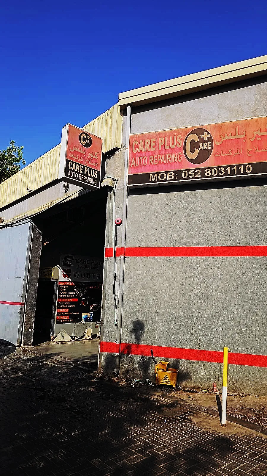 Care Plus Auto Repairing storefront sign in Al Quoz showing the workshop name and phone number