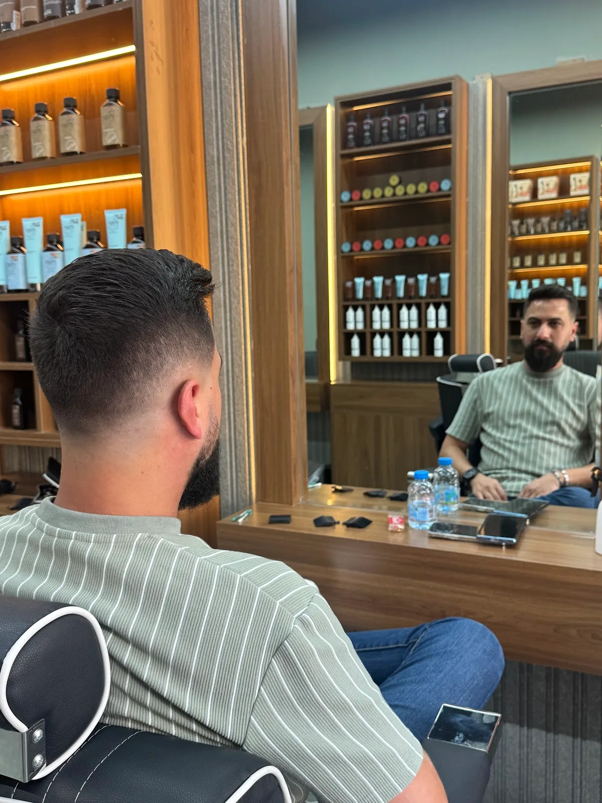 Client with a freshly shaped beard and faded haircut looking into the mirror