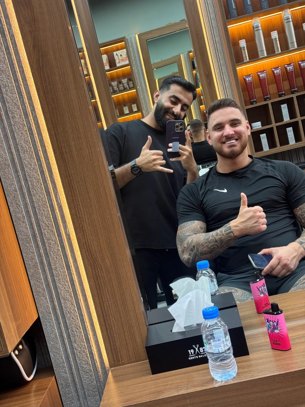 Happy client and barber giving a thumbs up in the mirror