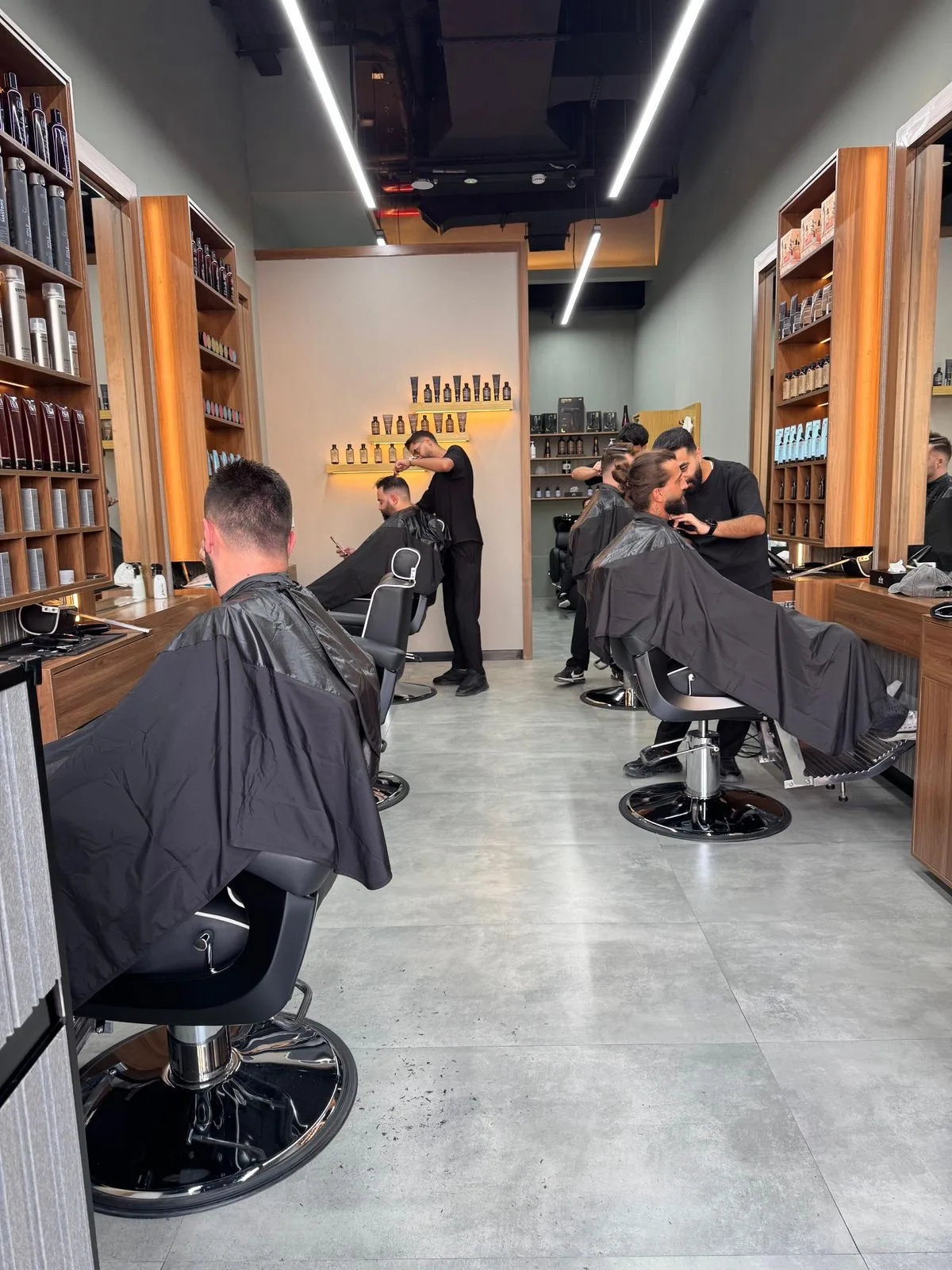 Barbers at work along the shop floor with clients in the chairs
