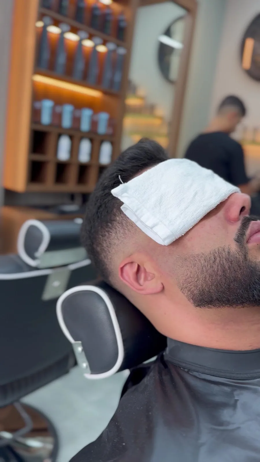 Guest relaxing in the barber chair with a hot towel over the face