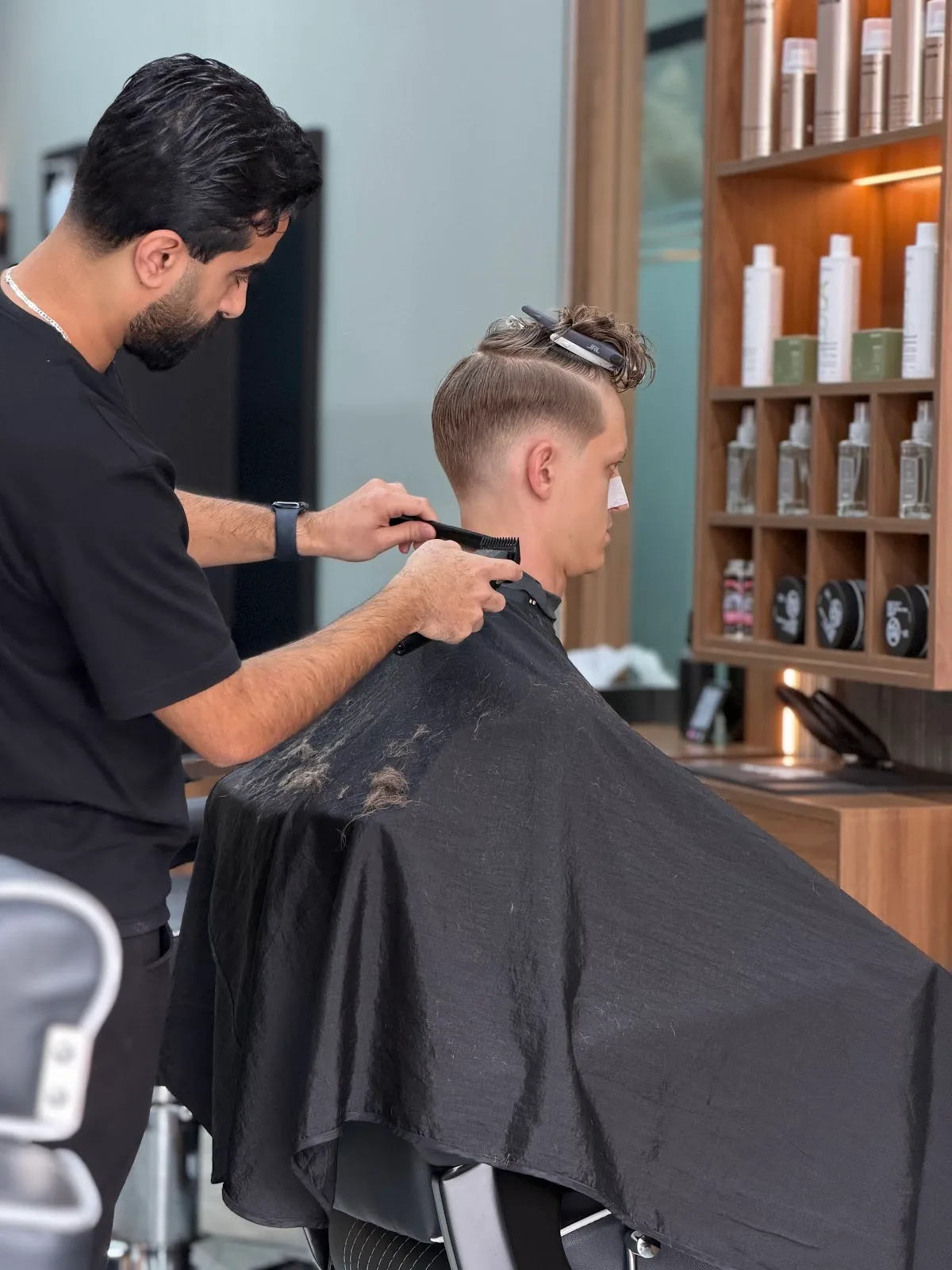 Barber combing and cleaning up a client's neckline with clippers