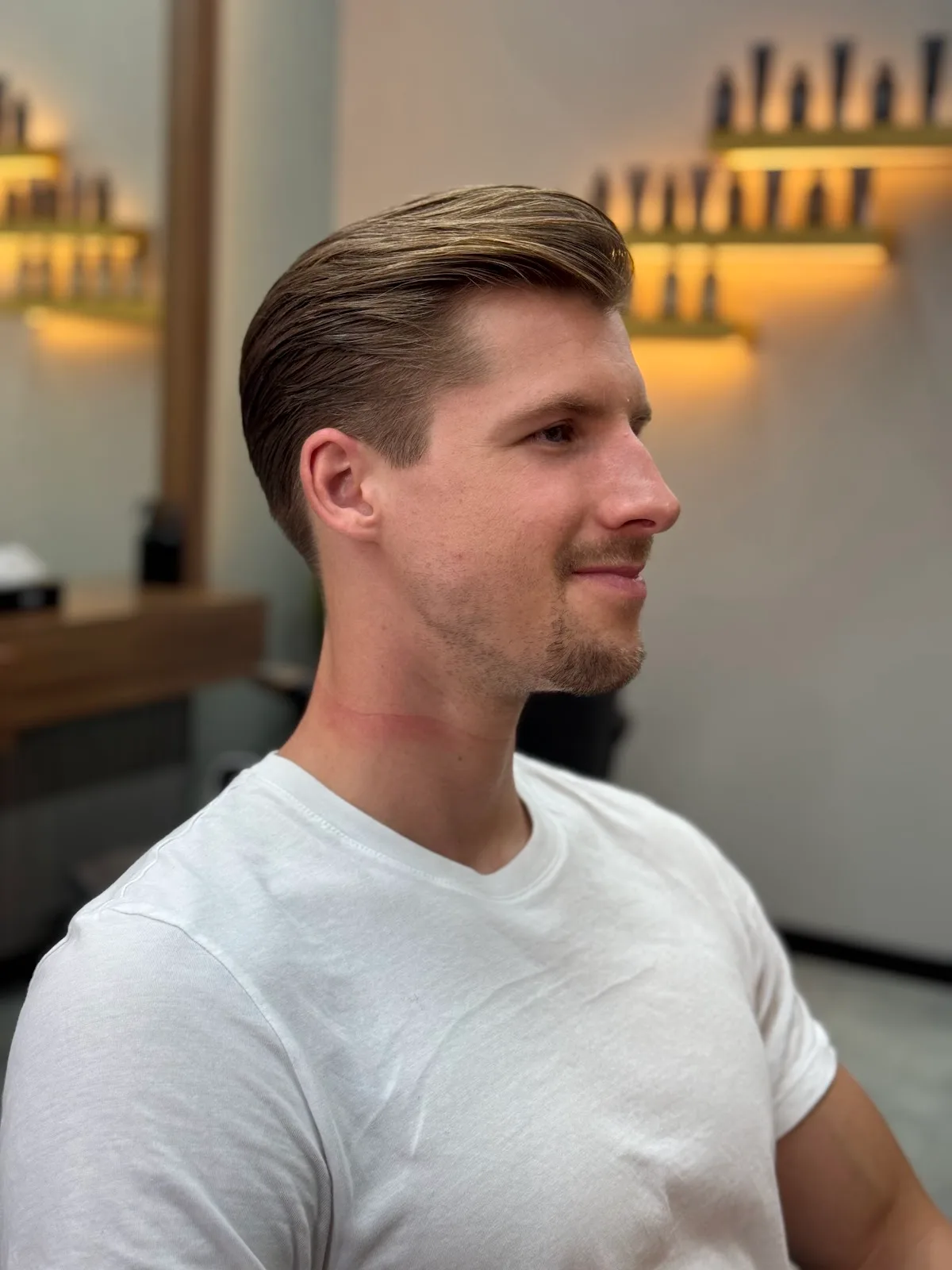 Side profile of a tidy slicked-back haircut with a clean taper