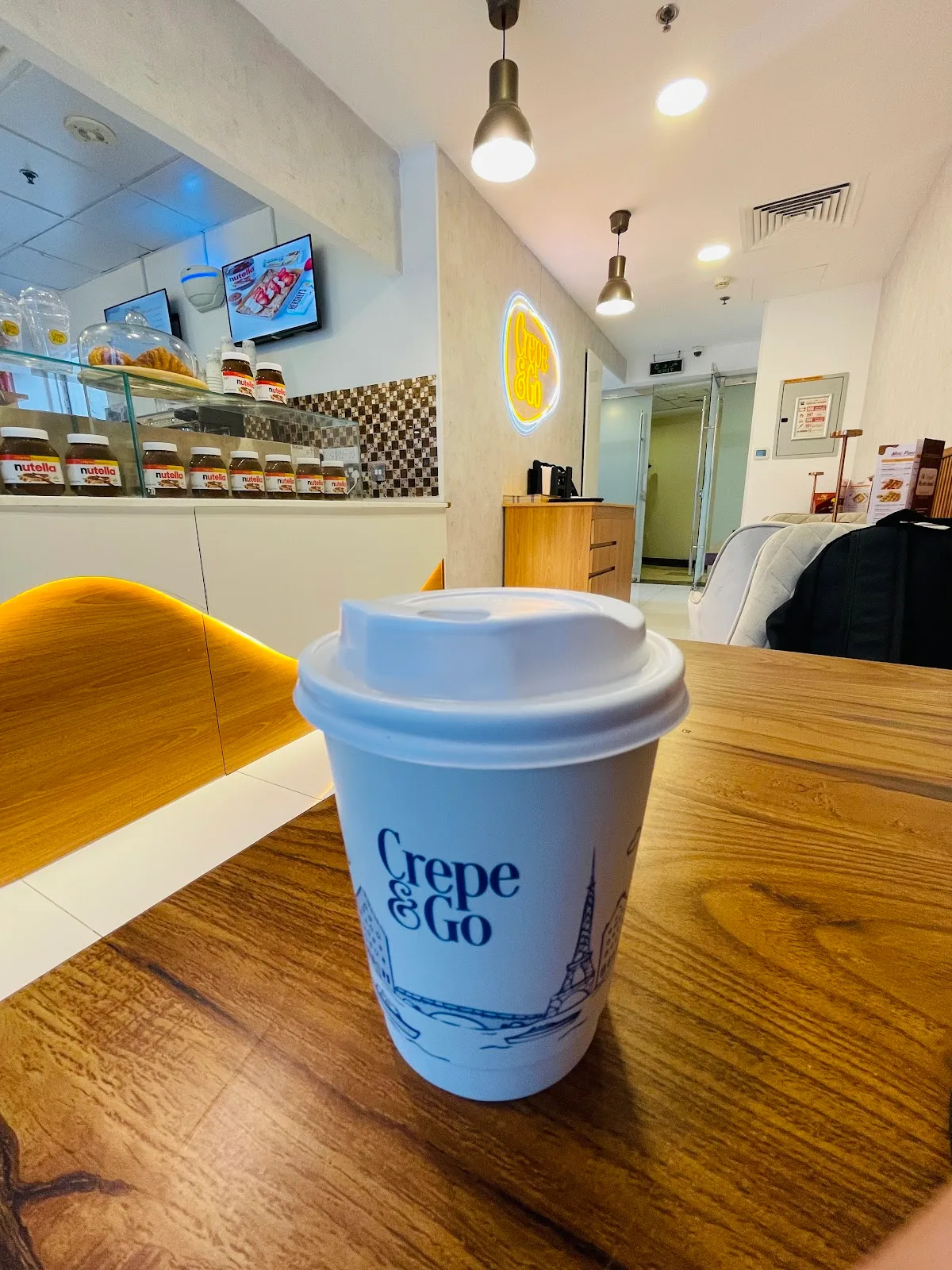 A Crepe&Go branded coffee cup with a Paris skyline illustration