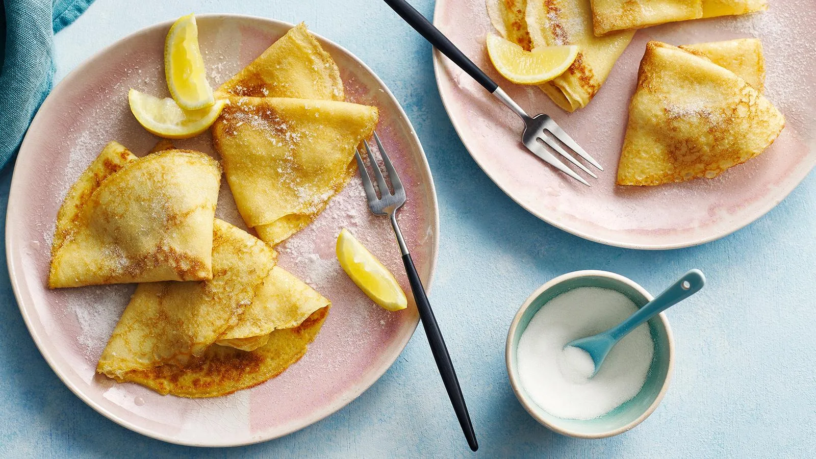 Folded crêpes dusted with sugar and served with lemon
