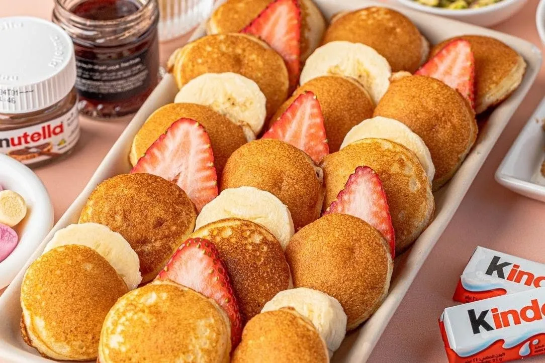 Tray of mini pancakes with strawberry and banana slices