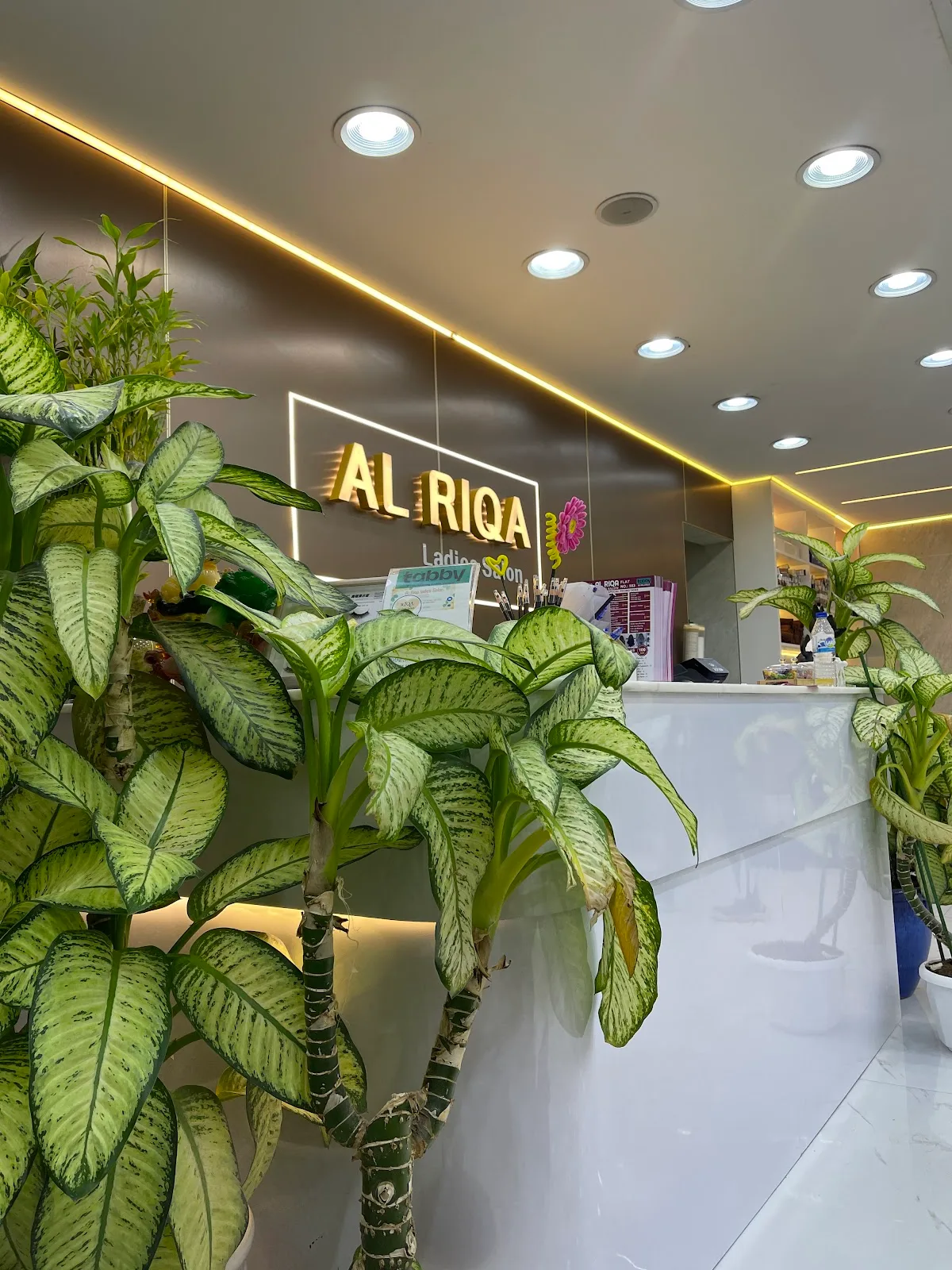 The plant-filled interior of Al Riqa Ladies Salon with the gold sign