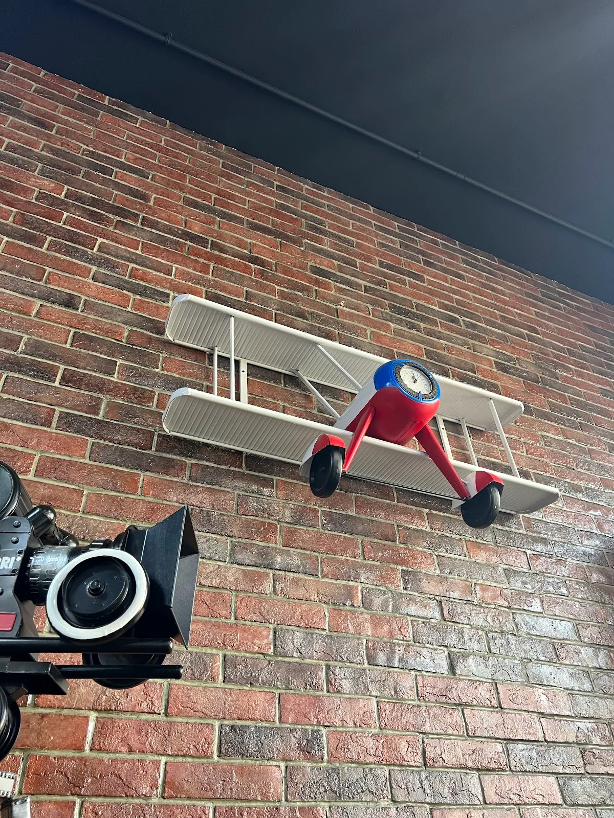 Model biplane clock and film-set props on the brick wall