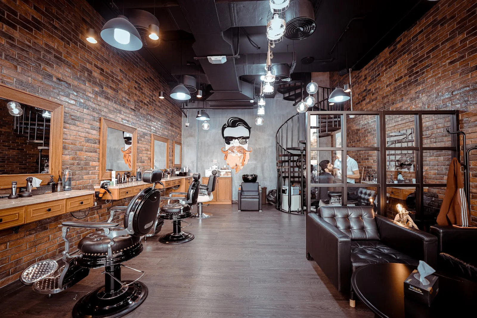 Wide view of The Stars Barber floor — a row of vintage barber chairs under exposed brick with a spiral staircase