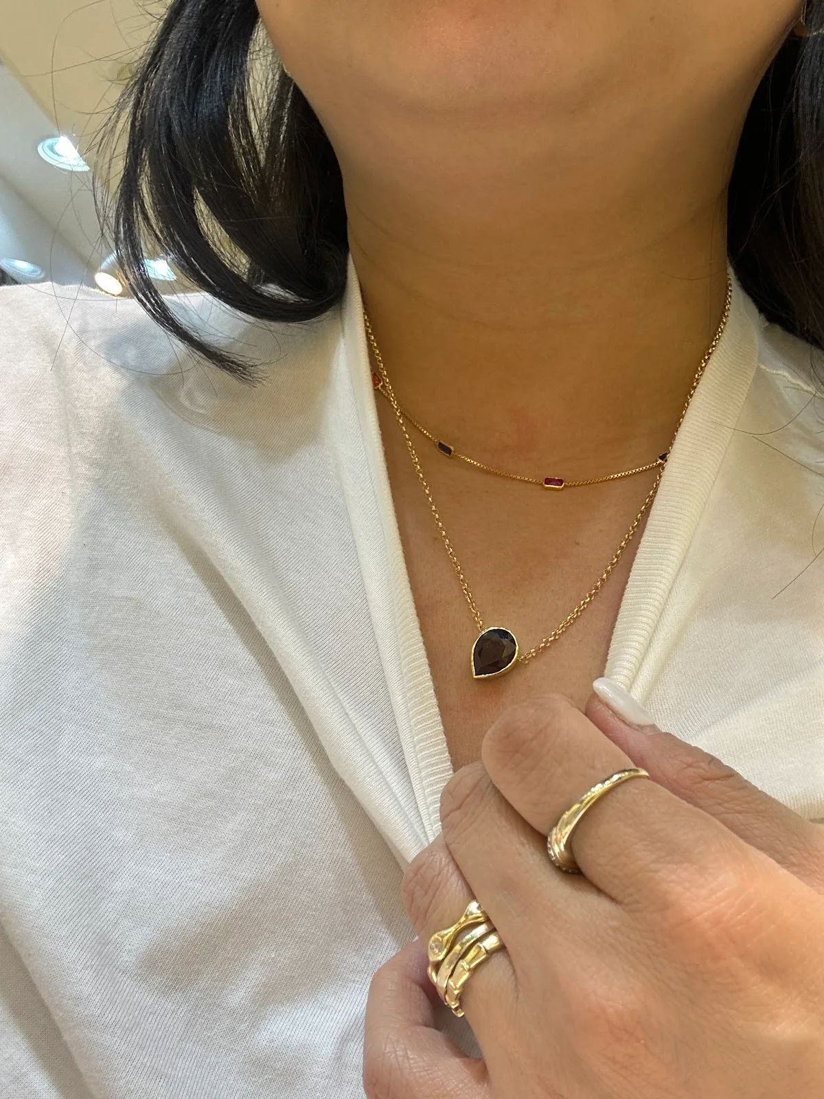 Layered gold necklaces and rings worn by a customer at Lee Mark Jewellery