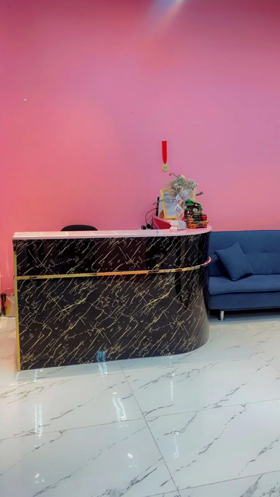 Wide view of the Pinky Touch reception with pink walls, marble desk and blue sofa