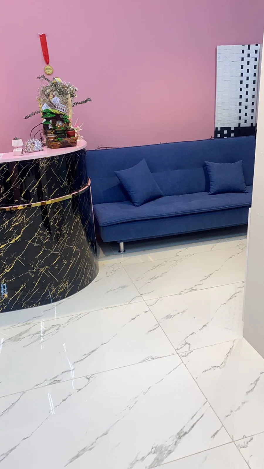 Reception lounge at Pinky Touch Beauty Saloon with pink walls and a marble desk