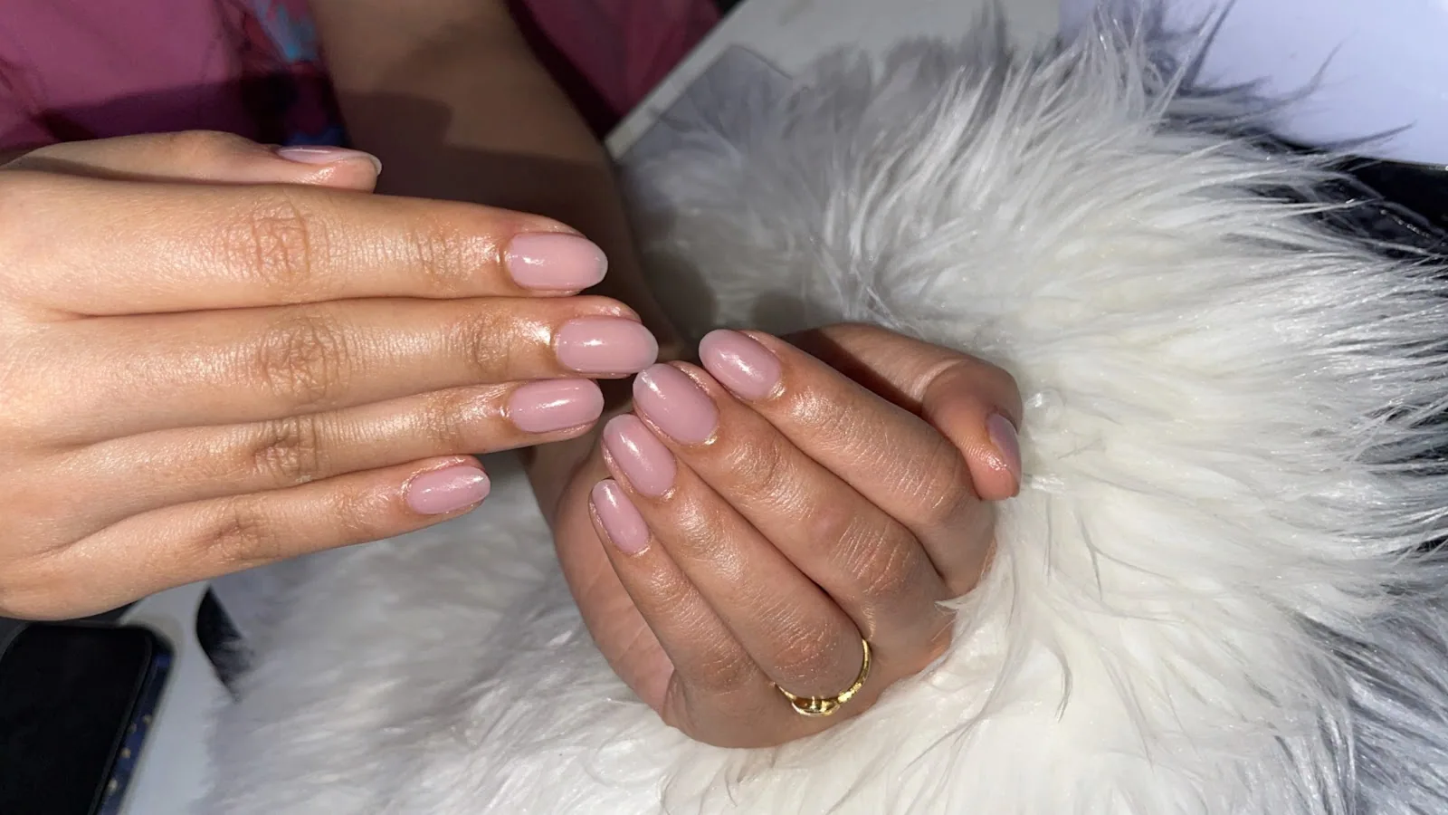Glossy nude manicure resting on soft fur